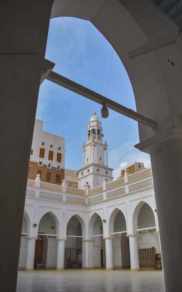 Beautiful mosque courtyard with arches and a tall tower, showcasing Islamic architecture.